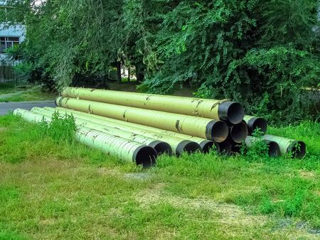 Large metal water pipes stacked in a pyramid on the grass.Industrial construction material. Summer day.の写真素材