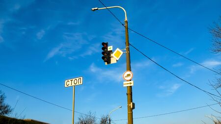 Traffic light and road signs on a blue sky background. Red traffic light. Traffic signs on a city street. Dnipro, Ukraine. The inscription on the sign (STOP).の写真素材