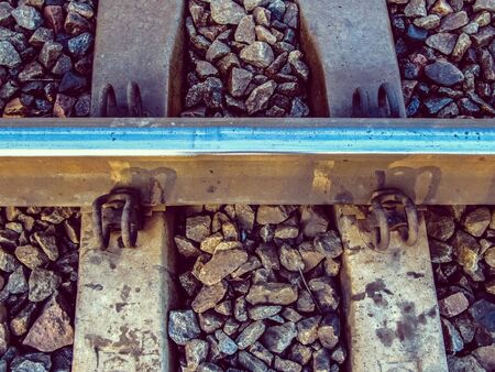 Part of the railway section close-up with rails and a concrete beams on a stone base from rubble.The Close-Up of a Rail Fastener, a Rail Line, and a Concrete Sleeper.の写真素材