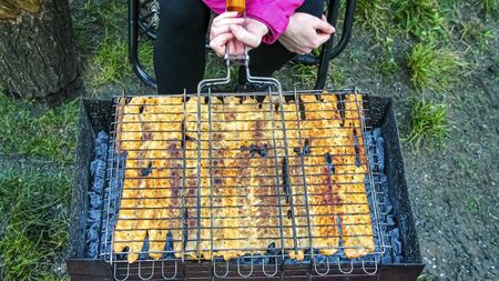 A woman cooks fried fish on a grill in a grid. Springtime outdoor recreation. Cooking outdoors.の写真素材