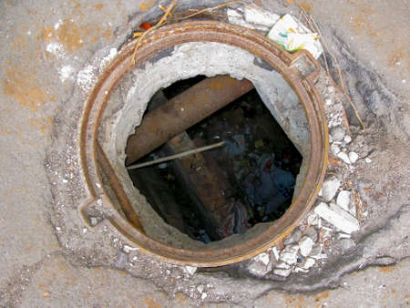 Top view of the dangerous open sewer manhole on the road, danger to people who walk along the city street. Close-up.の写真素材