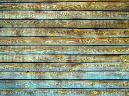 Background of brown wooden fence made of planks. The texture of an old rustic wooden fence made of flat processed boards. Wooden fence made of old boards with the inclusion of knots. Background design.の写真素材