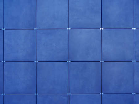 The wall is covered with blue square tiles. Modern wall design. Exterior decoration of the walls of the house and external facades with siding.の写真素材