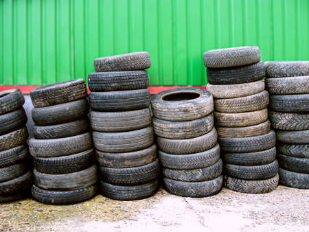 Old tires are stacked against the wall. Close-up of worn tires. A pile of old tires from used cars....