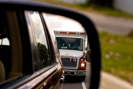 View of ambulence approaching in side view mirrorの写真素材
