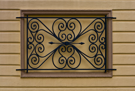 Window bars covering an old boarded and stuccoed windowの写真素材