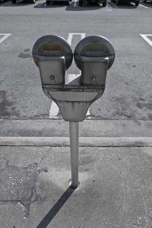 Parking meters in the sidewalk next to parking lotの写真素材