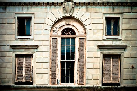 Bleach bypass image of windows in an old building with various damage and peeling paintの写真素材
