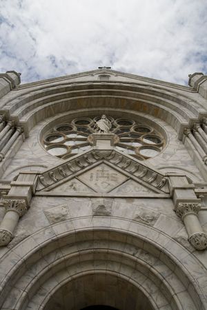 Front facade of a gothic church with rosette window and statuette from steep angle also showing arch of doorwayの写真素材