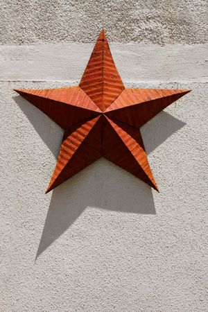 Red metal rustic country star hanging on an exterior wallの写真素材