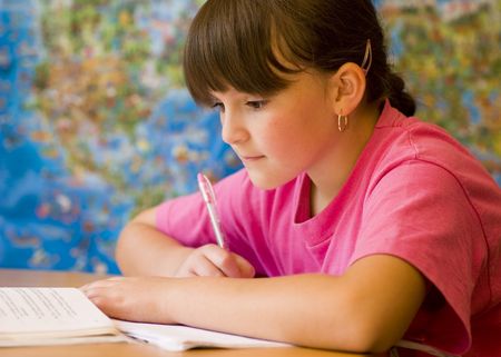 Concentrated young girl doing her school home-work.の写真素材