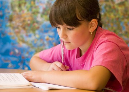 Concentrated young girl doing her school home-work.の写真素材