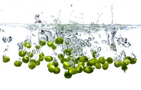 Peas splashing into water against a white backgroundの写真素材