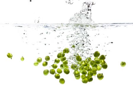 Peas splashing into water against a white backgroundの写真素材
