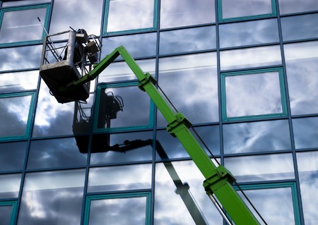 Window cleaner working on a glass facade in a gondola Window cleaner working on a glass facade in a gondola