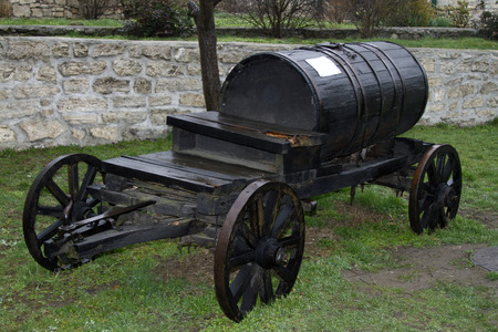 Old wooden barrel on cart. Vintage black barrel wagon transports water.の写真素材