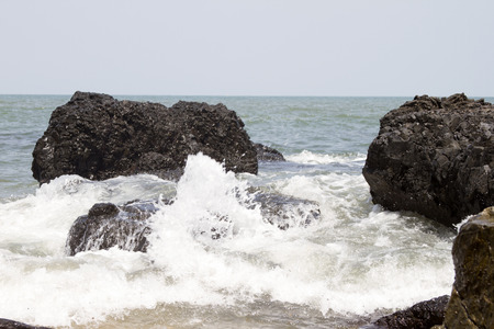 Beautiful waves of a beach of Goa, India. Wave crashing on the rocky reef.の写真素材