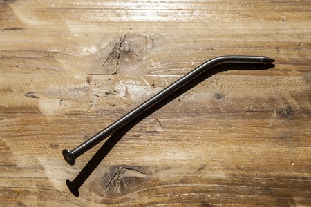 A large iron nail on the old wooden table.の写真素材