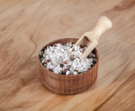 Large sea salt with red and black pepper in a wooden jar with a small wooden spoon on a beautiful wooden tray .の写真素材