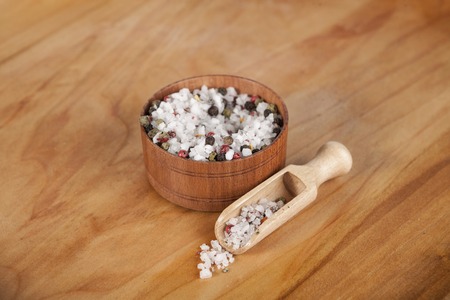 Large sea salt with red and black pepper in a wooden jar with a small wooden spoon on a beautiful wooden tray .の写真素材