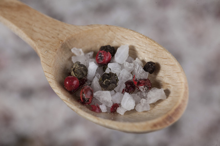 Large sea salt with red and black pepper in a wooden jar on wooden spoon close -up macro .の写真素材