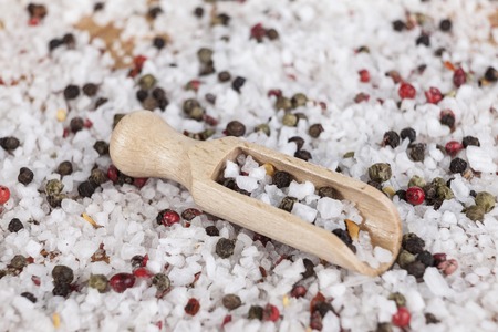 Large sea salt with red and black pepper  with a small wooden spoons on a beautiful wooden tray .の写真素材