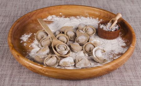 Homemade ravioli on a wooden tray with parsley and saltの写真素材