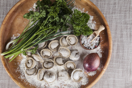Homemade ravioli on a wooden tray with parsley and saltの写真素材
