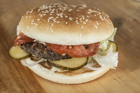 Fresh hamburger with a chop of marbled beef and fresh vegetables on a wooden background.の写真素材