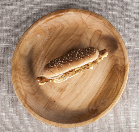Fresh tasty hot dog with fried onions and fresh lettuce with mustard on a wooden tray.の写真素材