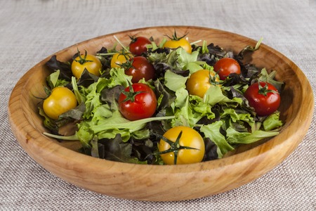 Fresh lettuce and red and yellow cherry tomatoes on a wooden tray.の写真素材