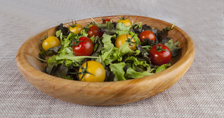 Fresh lettuce and red and yellow cherry tomatoes on a wooden tray.の写真素材