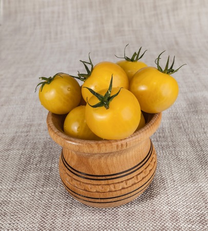 Fresh yellow cherry tomatoes in a wooden rustic jar.の写真素材