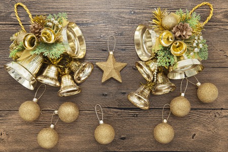 Glittering gold Christmas balls, bells, and star on wooden backgroundの写真素材