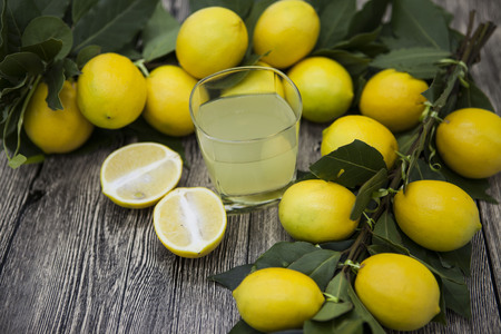 Fresh juicy lemons and a glass of homemade lemonade on a wooden background.の写真素材