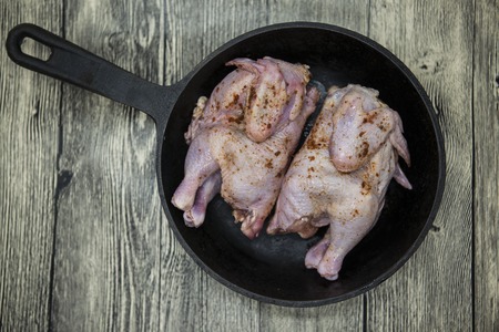 Two raw fresh chicken on iron pan  over wooden background