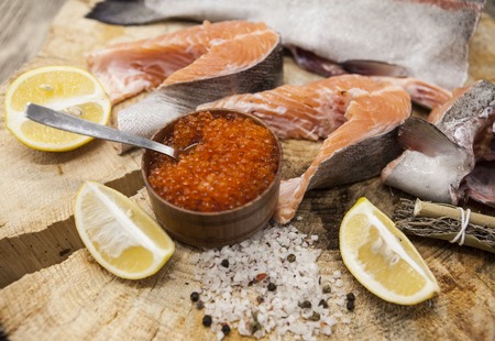 Fresh Norwegian rainbow trout with lemon red caviar, sea salt and onions on a wooden background.の写真素材