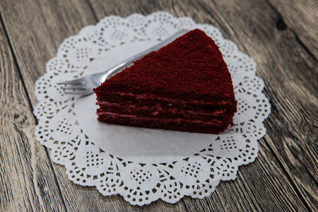 Fresh tasty sweet piece of  red velvet cake, on a white napkin and a dessert fork on a wooden...