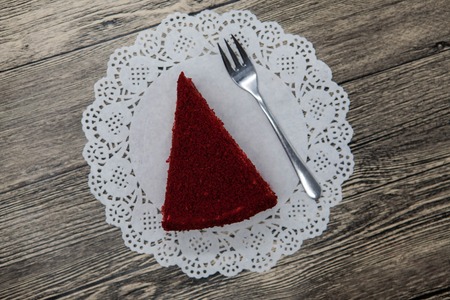 Fresh tasty sweet piece of  red velvet cake, on a white napkin and a dessert fork on a wooden background.の写真素材