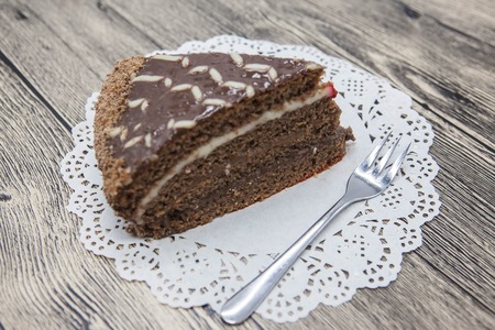 Fresh tasty sweet piece of  chocolate cake on a white napkin and a dessert fork on a wooden background.の写真素材