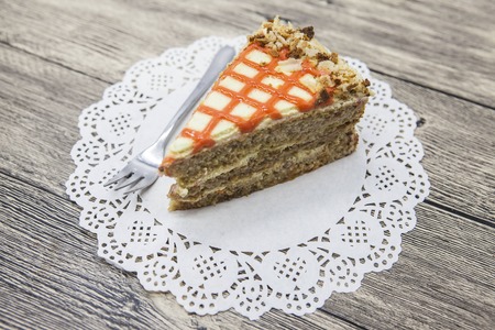 Fresh tasty sweet piece of  carrot cake on a white napkin and a dessert fork on a wooden background.の写真素材