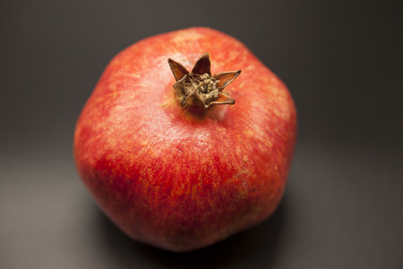 Spanish juicy ripe pomegranate closeup on a dark background.