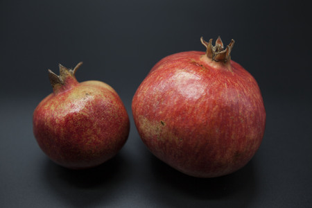 Two fruit juicy Spanish pomegranate on a dark backgroundの写真素材