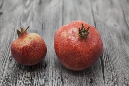 Two fruit juicy Spanish pomegranate on the wooden background.の写真素材