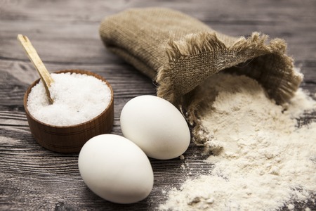Wheat flour in a canvas bag, a large salt shaker wood, raw eggs: set for making homemade bread dough...