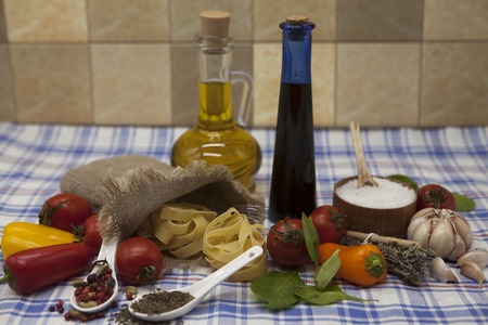 Beautiful set for the creation of the Sicilian pasta: cherry tomatoes, olive oil, balsamic sauce, garlic, spices, sea salt, salad on a rustic table.の写真素材