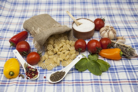 Rotelle  Italian pasta set for the creation : cherry tomatoes, olive oil, balsamic sauce, garlic, spices, sea salt, salad on a rustic table.の写真素材
