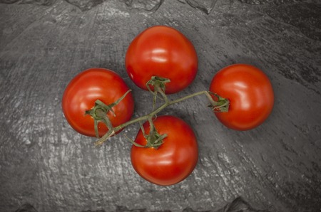 Fresh branch of red Sicilian ripe tomatoes on a stone background.の写真素材