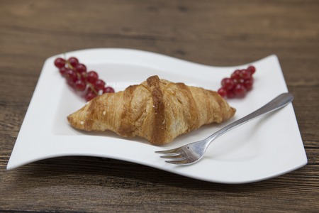 Dukan Diet. Fresh delicious croissant at Dukan Diet on a porcelain plate with a spoon on a wooden backgroundの写真素材