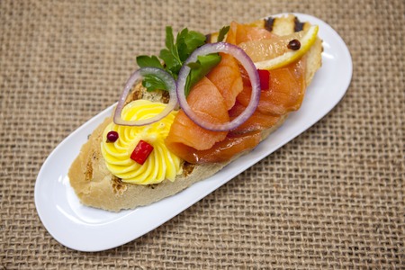 Fresh Spanish tapas on bread baguette smoked Norwegian salmon with black olive butter, herbs and...